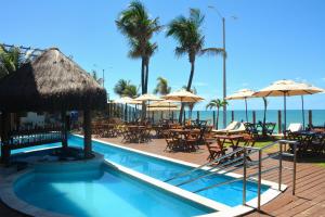 ein Pool mit Tischen und Sonnenschirmen und das Meer in der Unterkunft Na praia - Elegance 202 Luxo - Lateral in Natal