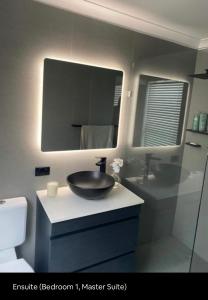 La salle de bains est pourvue d'un lavabo et d'un miroir. dans l'établissement 5 OClock Somewhere 6BR sleeps 18 with Kids Retreat, à Port Macquarie