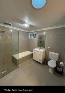 a bathroom with a toilet and a shower and a sink at 5 OClock Somewhere 6BR sleeps 18 with Kids Retreat in Port Macquarie