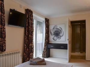 a bedroom with a television and a window with curtains at Sunningdale Cottage in Chapel Saint Leonards