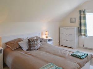 a bedroom with a bed and a dresser and a window at Barrowswood in Cheddar