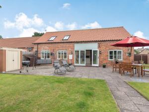 a patio with a table and chairs and an umbrella at Old Foundry Cottage in Burgh le Marsh