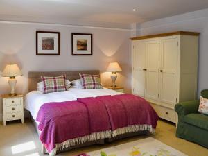 a bedroom with a large bed with a purple blanket at Prideaux Farmhouse in Luxulyan