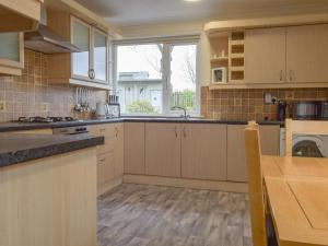 a kitchen with white cabinets and a sink and a window at The Shieling in Biggar