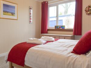 a bedroom with a bed with red curtains and a window at The Shieling in Biggar