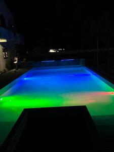 una piscina con luz verde y azul por la noche en White Elephant Villa & Restaurant en Beruwala