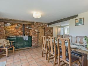 a kitchen with a table and chairs and a brick wall at Wherrymans Cottage in Coltishall