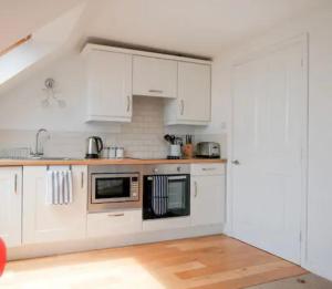 a white kitchen with white cabinets and a wooden floor at Y2 guest house in London