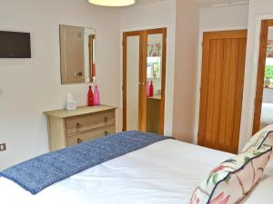 a bedroom with a bed and a dresser and a television at The Wagon House in Luxulyan