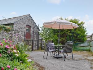 una mesa y sillas con una sombrilla en el jardín en The Granary en Egloskerry