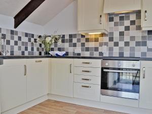 a kitchen with white cabinets and black and white tiles at The Granary in Egloskerry