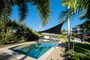 a swimming pool in a resort with palm trees at Pavillions on 1770 in Agnes Water