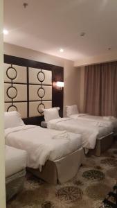 a hotel room with three beds with white sheets at فندق البيرق in Makkah