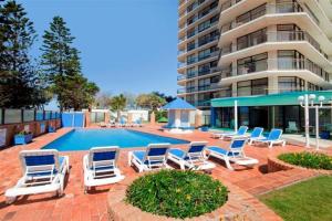 a pool with lounge chairs and a building at Surfers Paradise Apartment With Amazing Views in Gold Coast