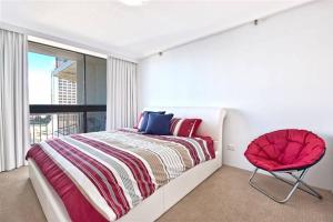 a bedroom with a bed and a red chair at Surfers Paradise Apartment With Amazing Views in Gold Coast