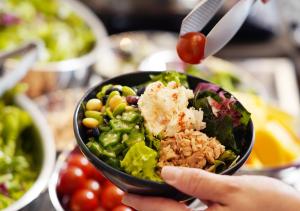 a person is holding a bowl of salad at APA Hotel TKP Keikyu Kawasaki Ekimae in Kawasaki