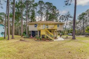 a small house with a porch and a deck at Woodsy Retreat, steps to Bay - Hot tub! in Gulf Breeze