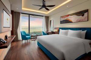 een slaapkamer met een groot bed en een blauwe stoel bij The Watson Premium HaLong Hotel in Ha Long