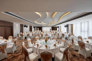un salón de banquetes con mesas blancas y sillas blancas en The Watson Premium HaLong Hotel, en Ha Long