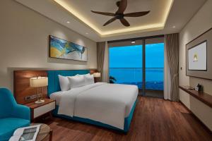 The Watson Premium HaLong Hotel في ها لونغ: غرفة نوم بسرير كبير وكرسي ازرق