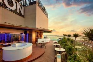 a hotel patio with tables and chairs and a sunset at The Watson Premium HaLong Hotel in Ha Long