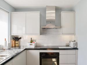 a kitchen with white cabinets and a stove top oven at Dougies Retreat in Pevensey