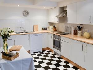 a kitchen with white cabinets and a black and white checkered floor at Woods Barn in Beckermonds