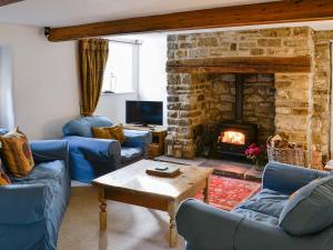 a living room with blue couches and a fireplace at Woods Barn in Beckermonds