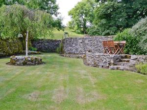 Woods Barn في Beckermonds: جدار حجري مع كرسي وشجرة في ساحة