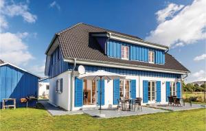 ein blau-weißes Haus mit einem Tisch und einem Sonnenschirm in der Unterkunft Ferienhaus 5 Altefähr in Altefähr