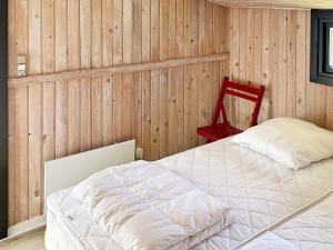 a bedroom with a white bed and a red chair at Holiday home Hadsund CXLIII in Hadsund