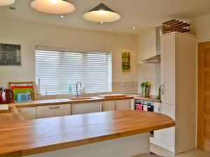 a kitchen with white cabinets and a wooden counter top at Riverbank Cottage in Althorpe
