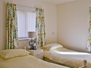 a bedroom with two beds and a window with curtains at Riverbank Cottage in Althorpe