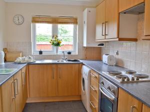 a kitchen with wooden cabinets and a sink at Fairy Cottage in Old Newton