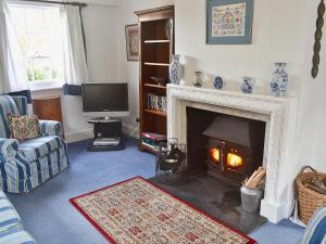 sala de estar con chimenea y TV en Keepers Cottage, en Helford Passage