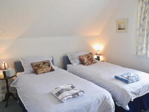 2 camas en una habitación con sábanas blancas en Keepers Cottage, en Helford Passage