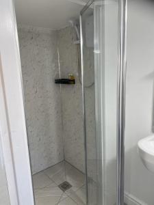 eine Dusche mit Glastür neben einem Waschbecken in der Unterkunft Modern Guest house with private entrance in Manchester