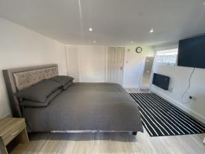 a bedroom with a large bed and a flat screen tv at Modern Guest house with private entrance in Manchester