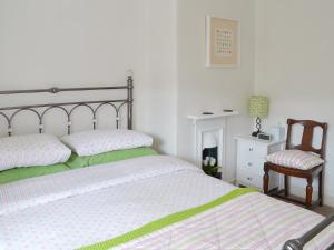 a white bedroom with a bed and a chair at Lavender Cottage in Buckfastleigh