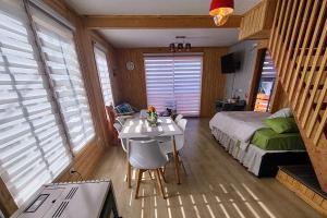 1 dormitorio con 1 cama y 1 mesa con sillas en Inversiones MM Gallardo SPA - Altos de Yaldad Cabañas en Quellón