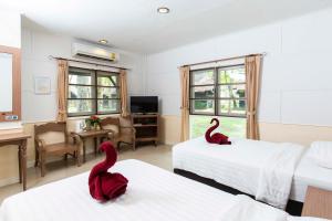 two red swans sitting on two beds in a hotel room at The Legacy River Kwai Resort in Kanchanaburi City