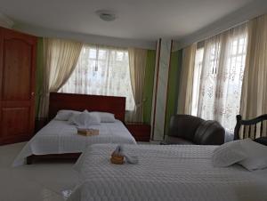 1 Schlafzimmer mit 2 Betten, einem Stuhl und Fenstern in der Unterkunft CASA DE LA ABUELITA in Choachí
