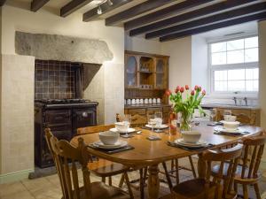 a dining room with a wooden table and a kitchen at Groudd Hall Cottage in Cerrig-y-Druidion