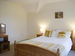 a bedroom with a wooden bed with two pillows at Groudd Hall Cottage in Cerrig-y-Druidion