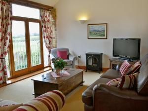 a living room with a tv and a couch and a table at New Park Farm - Church Cottage in Ireby