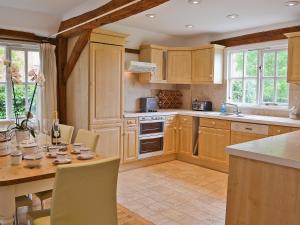 a kitchen with wooden cabinets and a table with chairs at Priory Barn in Weald