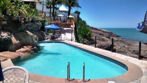 a swimming pool with the ocean in the background at Hotel Pontal das Rochas in Iriri