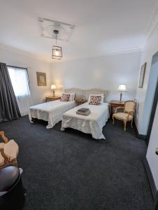 a hotel room with two beds and a table and chairs at Toodyay Manor in Toodyay
