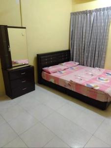 a bedroom with a bed and a dresser and a mirror at Raja Homestay Kluang in Kluang