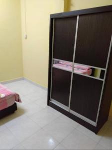 a bedroom with a black cabinet with pink clothes at Raja Homestay Kluang in Kluang